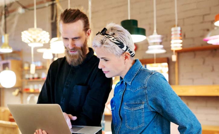 two co-workers looking at a laptop