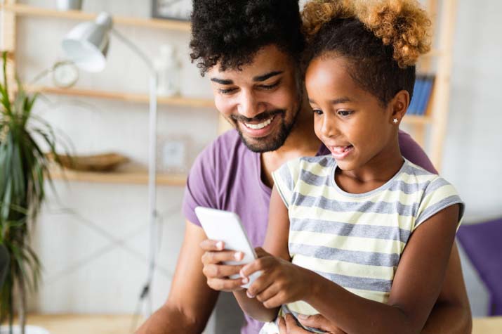 father and daughter playing on a phone