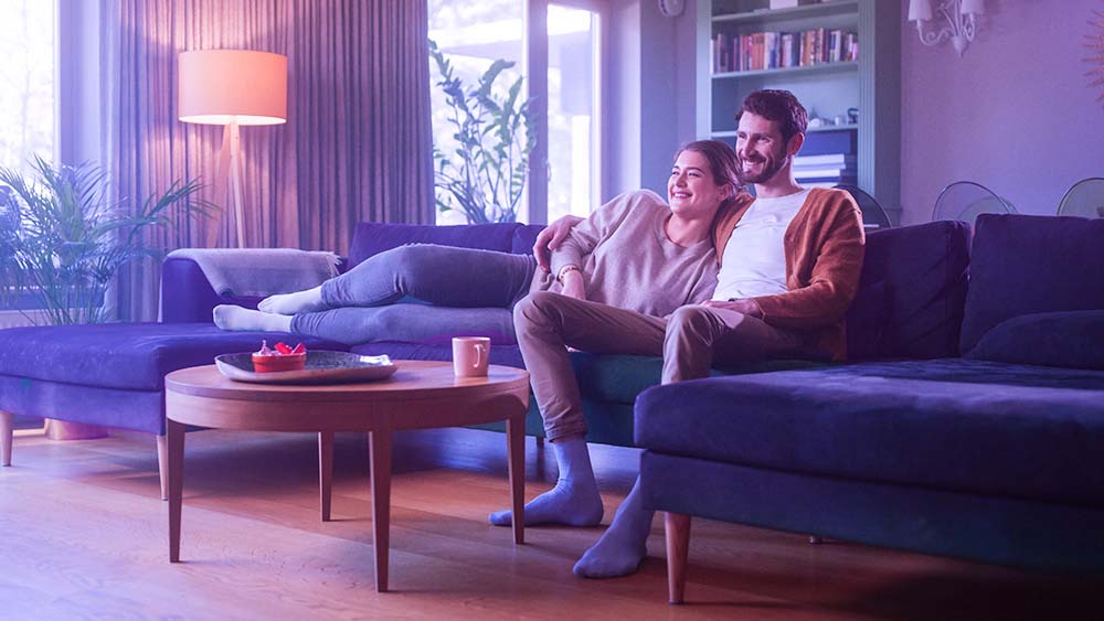 A couple watching tv and laughing on a couch