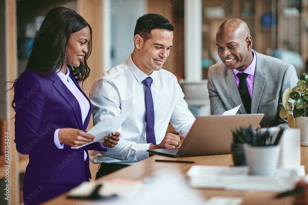 2 men and a woman looking at a laptop